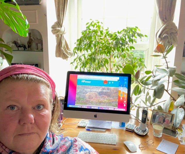 A selfie of Jenny in front of a laptop with the visit Dartmoor website on the screen